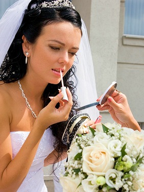 Braut macht sich Make-Up mit Spiegel und Lippenstift