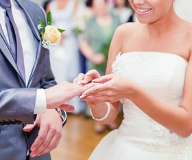 Braut steckt ihrem Mann den Ring an Hochzeitsringe austauschen